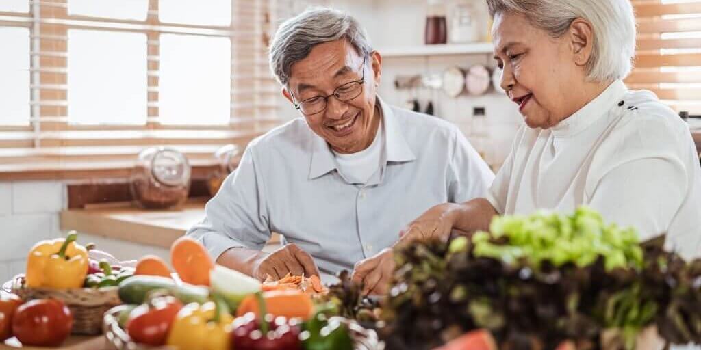 Senior Asian couple love cooking together in the kitchen with happiness